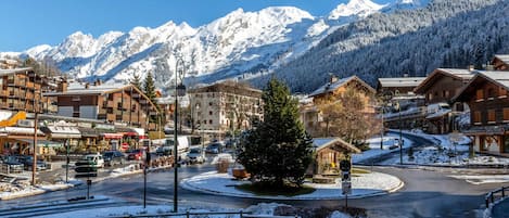 A snow-covered mountain town with buildings, a roundabout, and a view of snow-capped mountains.