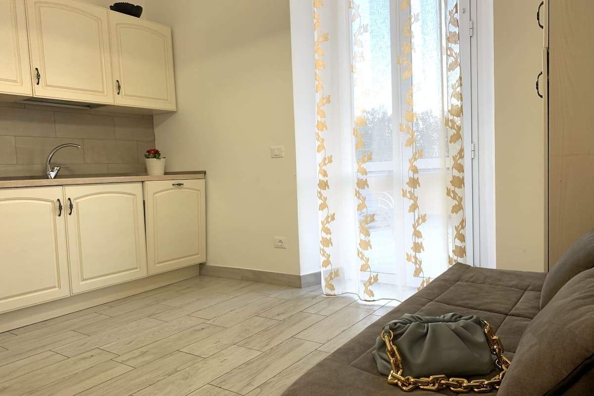 Una cocina moderna con armarios blancos, un lavamanos y una ventana con cortinas florales.