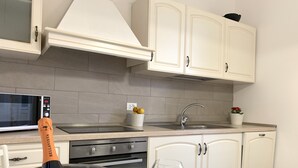 A modern kitchen with white cabinets, a stainless steel sink, and a microwave.