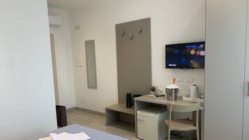 Una camera d'albergo con un letto, una scrivania con un computer, una televisione e un minibar.