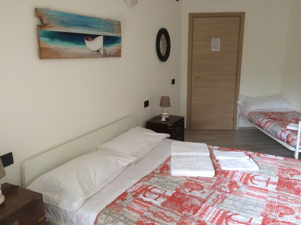 Un dormitorio con cama, mesita de noche, lámpara, un cuadro y una puerta.