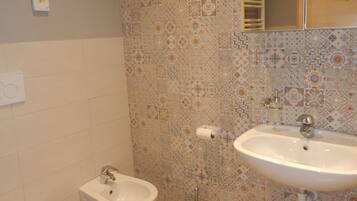 A bathroom with a bidet, a sink, and a mirror.