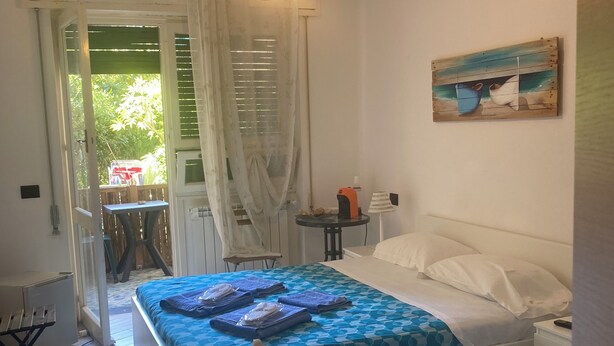 A bedroom with two beds, a painting, and a view through a window. - Guest House Berzefi (Bergeggi)