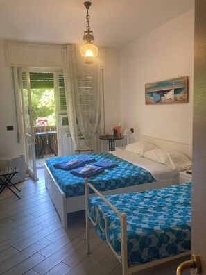 A bedroom with two beds, a painting, and a view through a window. - Guest House Berzefi (Bergeggi)