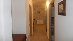 A narrow hallway with a radiator, a wooden door, and a framed picture on the wall. - Guest House Berzefi (Bergeggi)