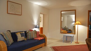 Una sala de estar con un sofá, una mesita, un espejo y una lámpara de pie.