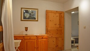 Una habitación con un armario de madera, un cuadro en la pared y una puerta que da a otra estancia.