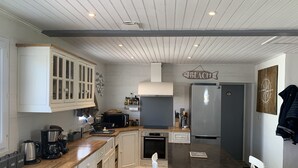 A modern kitchen with white cabinetry, a central island, and a built-in microwave. - Renovated house Ile de Noirmoutier (L'Epine), in a quiet dead end, garden! (L'EPINE)