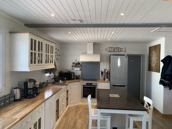 A modern kitchen with white cabinetry, a central island, and a built-in microwave.