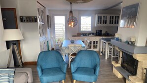 A cozy living room with a sofa, two blue armchairs, a dining table, and a fireplace. - Renovated house Ile de Noirmoutier (L'Epine), in a quiet dead end, garden! (L'EPINE)