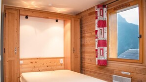 A room with a bed, wooden walls, a window with a view, and a quilt hanging on the wall. - 1st floor, balcony, parking, tv, ski locker, 23m², Pra Loup (Uvernet-Fours)