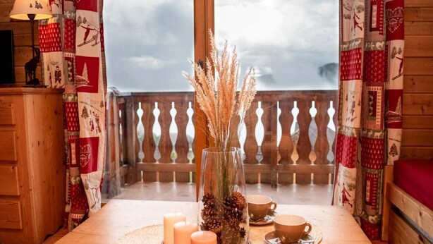 A wooden table with candles, a glass vase with pinecones, and a cup on a balcony with patterned curtains. - 2nd floor, balcony, parking, tv, ski locker, 38m², Pra Loup (Uvernet-Fours)