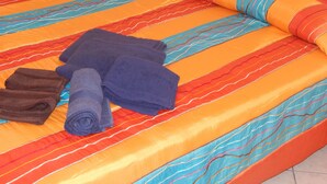 Uma cama com colcha listrada e toalhas enroladas.