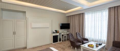 A hotel room with a bed, a seating area with a table and chairs, a TV, and a wardrobe.