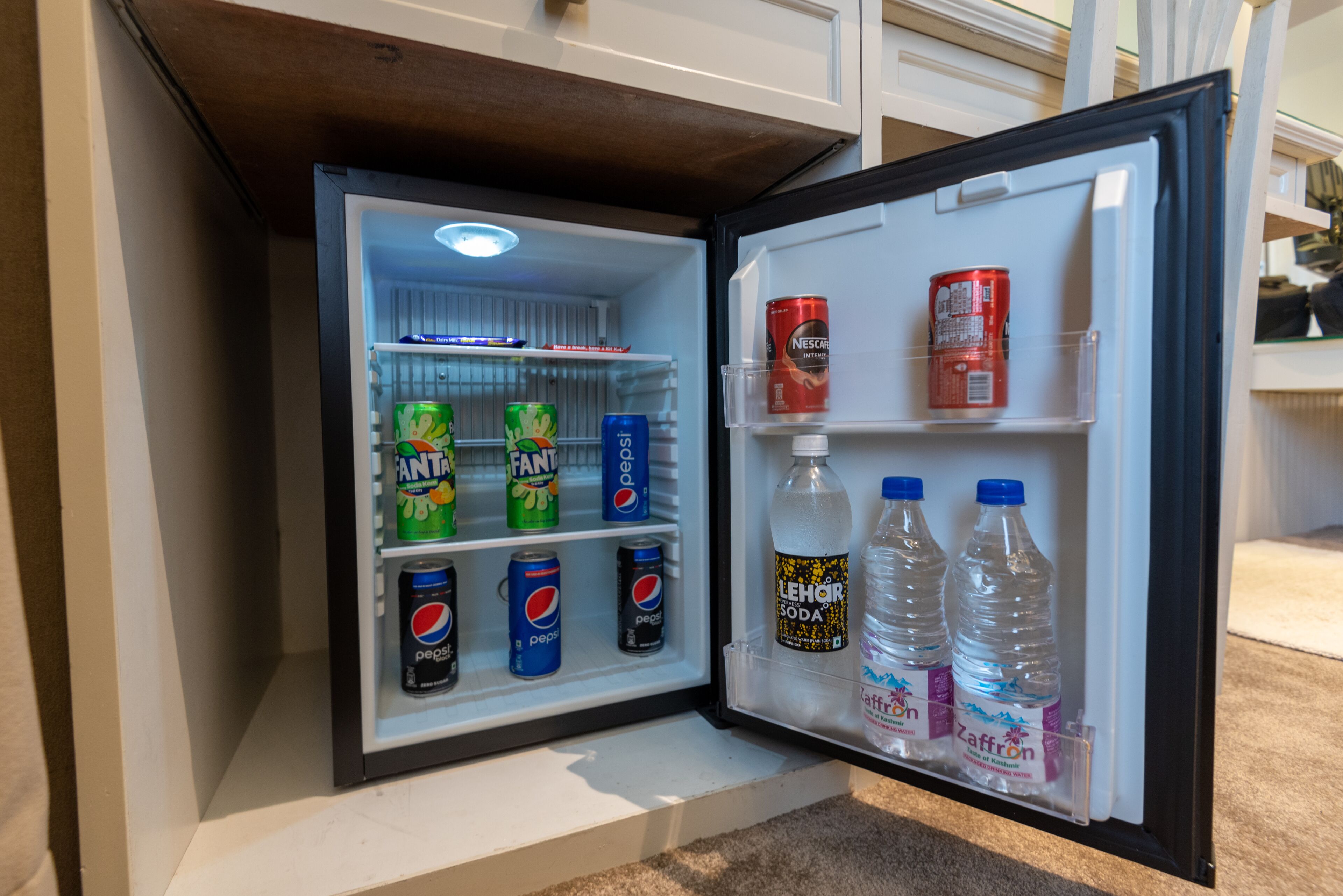 Un mini refrigerador con bebidas, incluyendo Fanta, Pepsi y botellas de agua.
