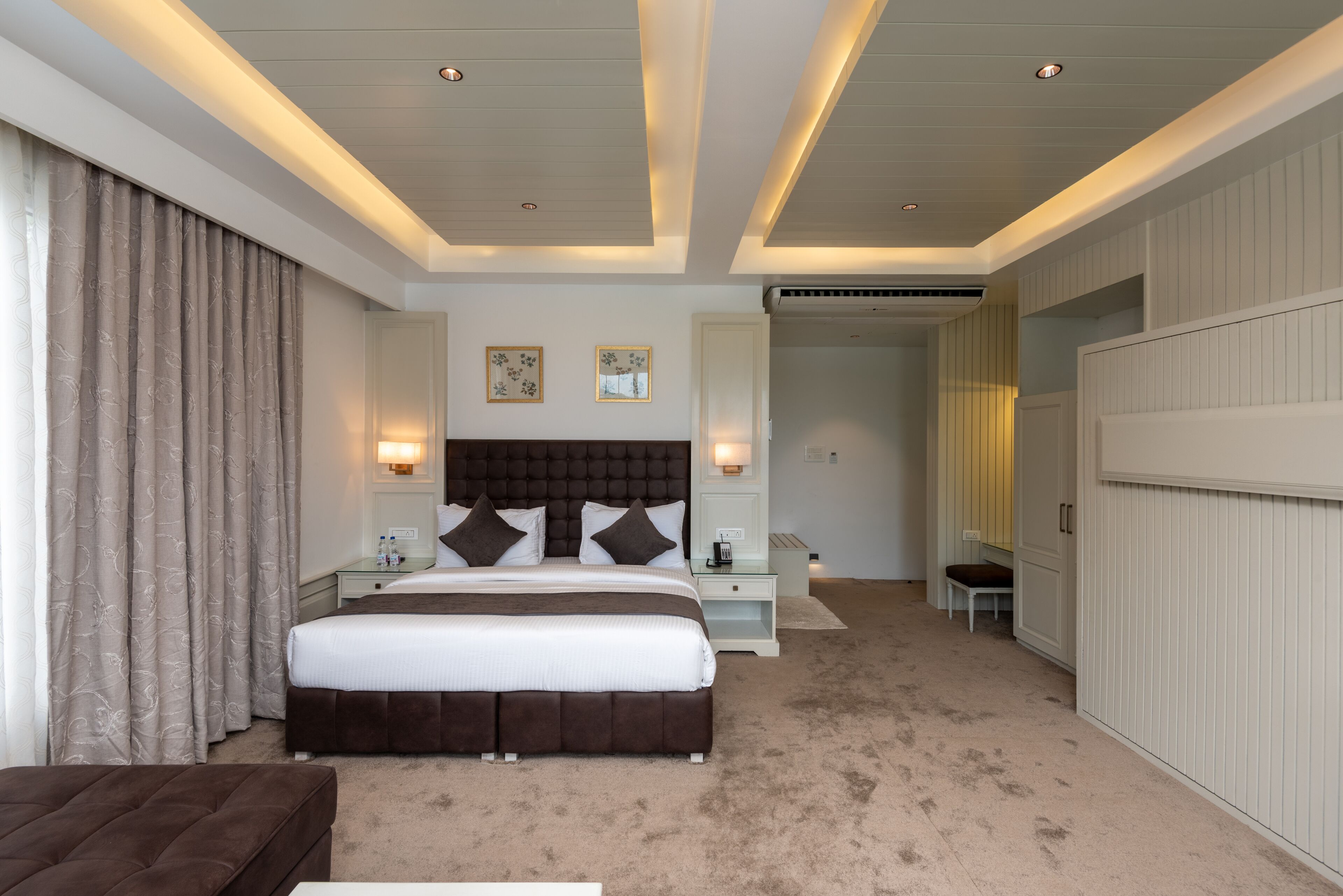 A hotel room with a large bed, bedside tables, a chair, and a wardrobe.
