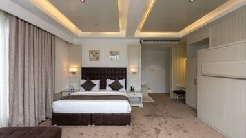 A hotel room with a large bed, bedside tables, a chair, and a wardrobe.