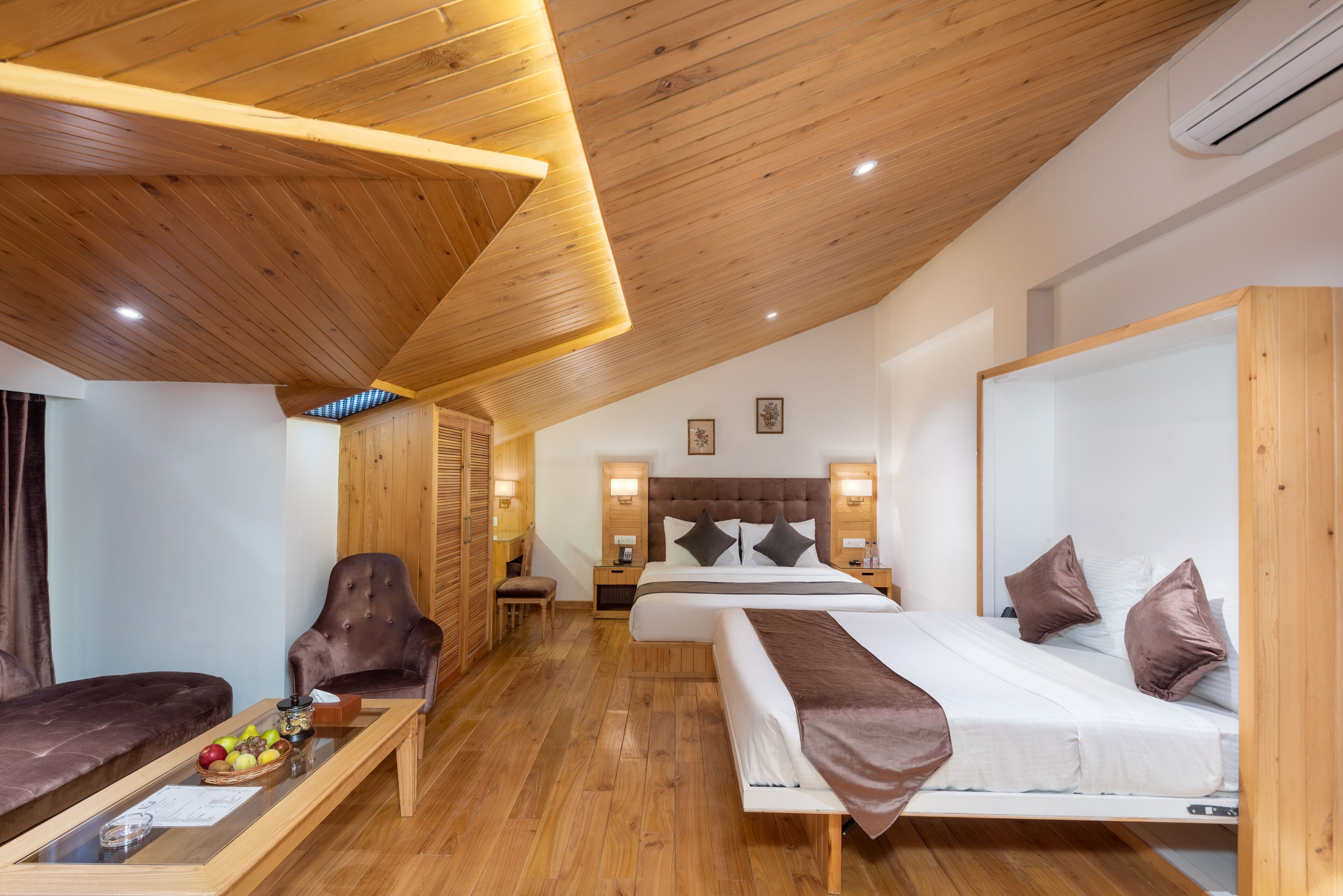 A modern hotel room with a wooden ceiling, two beds, a sofa, and a dining table.