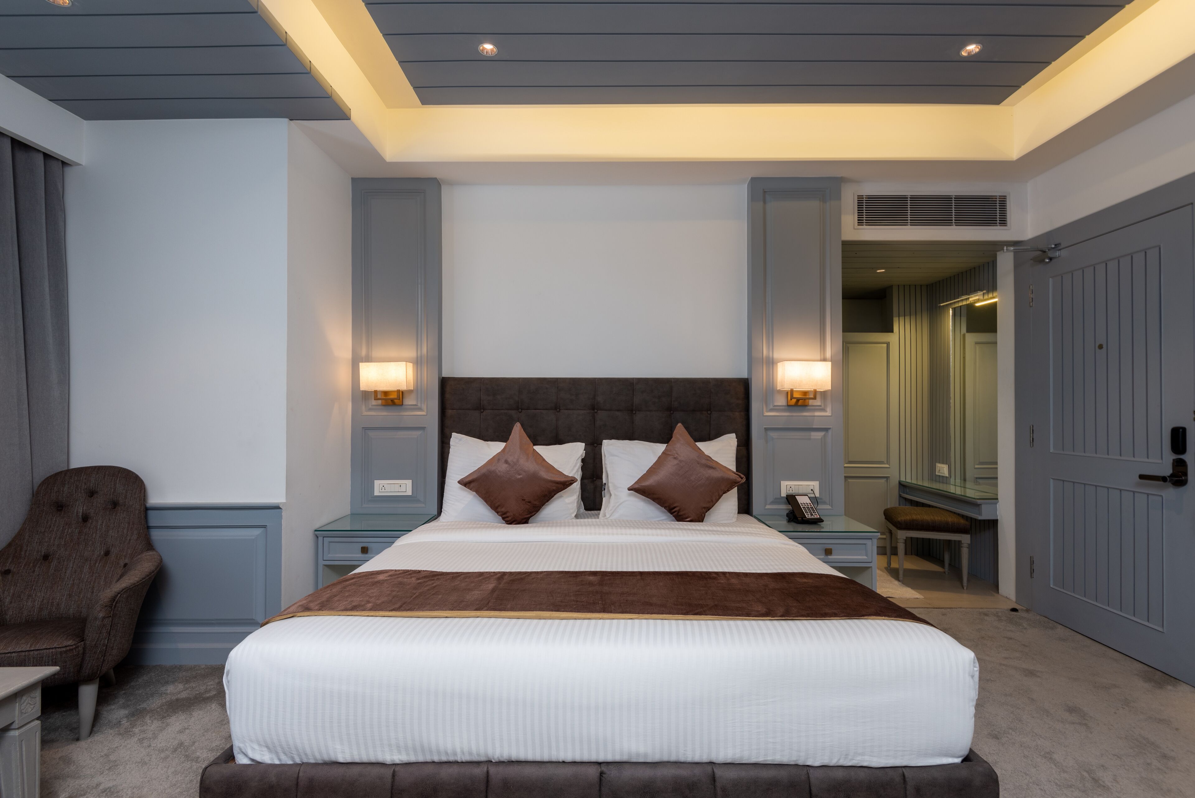 A neatly arranged bedroom with a large bed, bedside tables, a chair, and a walk-in closet.