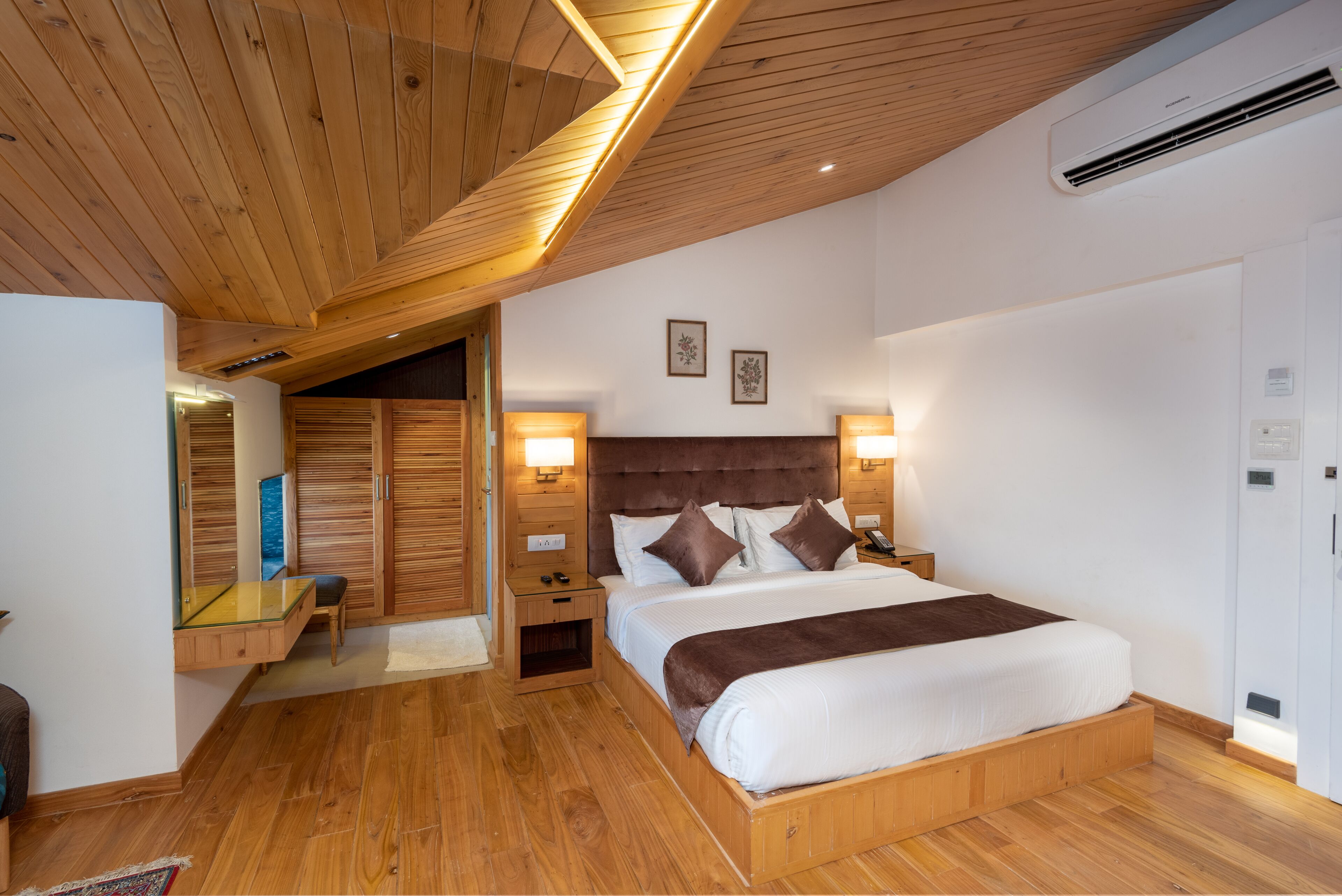 A bedroom with a wooden ceiling, a large bed, bedside lamps, a nightstand, a mirror, and a wardrobe.