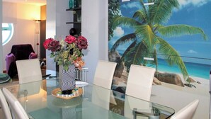 Un comedor moderno con una mesa de vidrio, sillas blancas y un jarrón con flores.