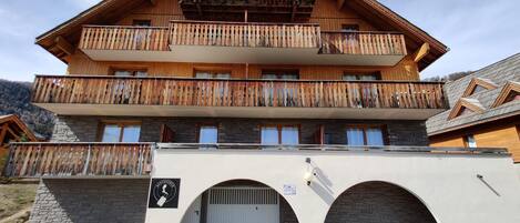 A multi-story wooden building with balconies, stone walls, and a sign indicating a hotel.