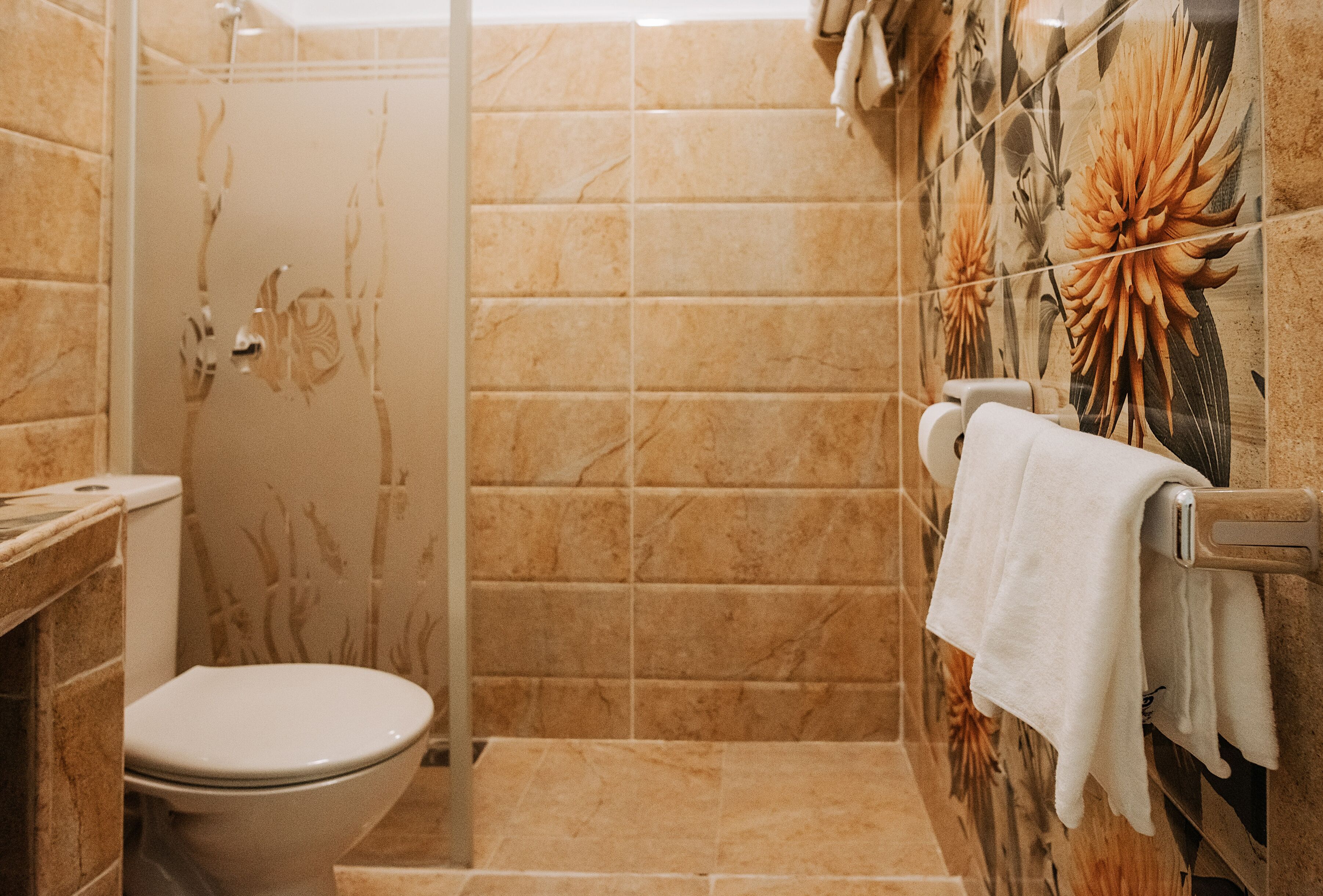 A bathroom with a toilet, a shower, and a towel rack.
