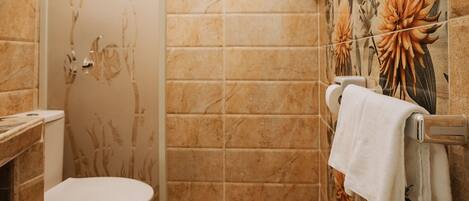 A bathroom with a toilet, a shower, and a towel rack.