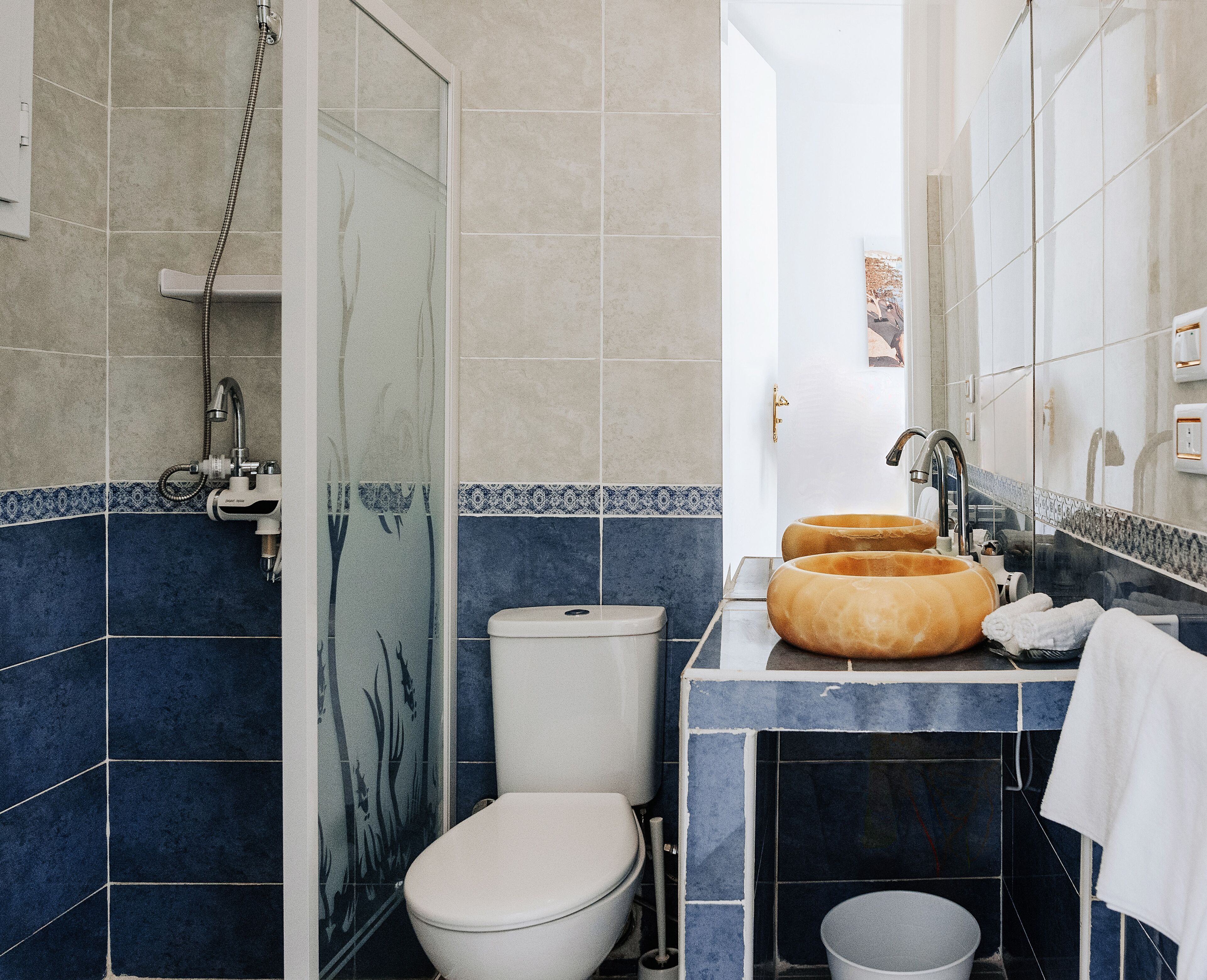 A bathroom with a toilet, a shower, and a sink with a mirror.