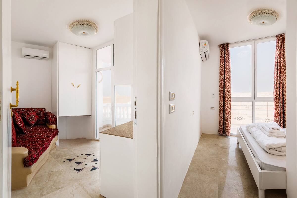 Ein Schlafzimmer mit einem Bett, einem Schlafsofa, einem Spiegel und einem Fenster mit Vorhängen.