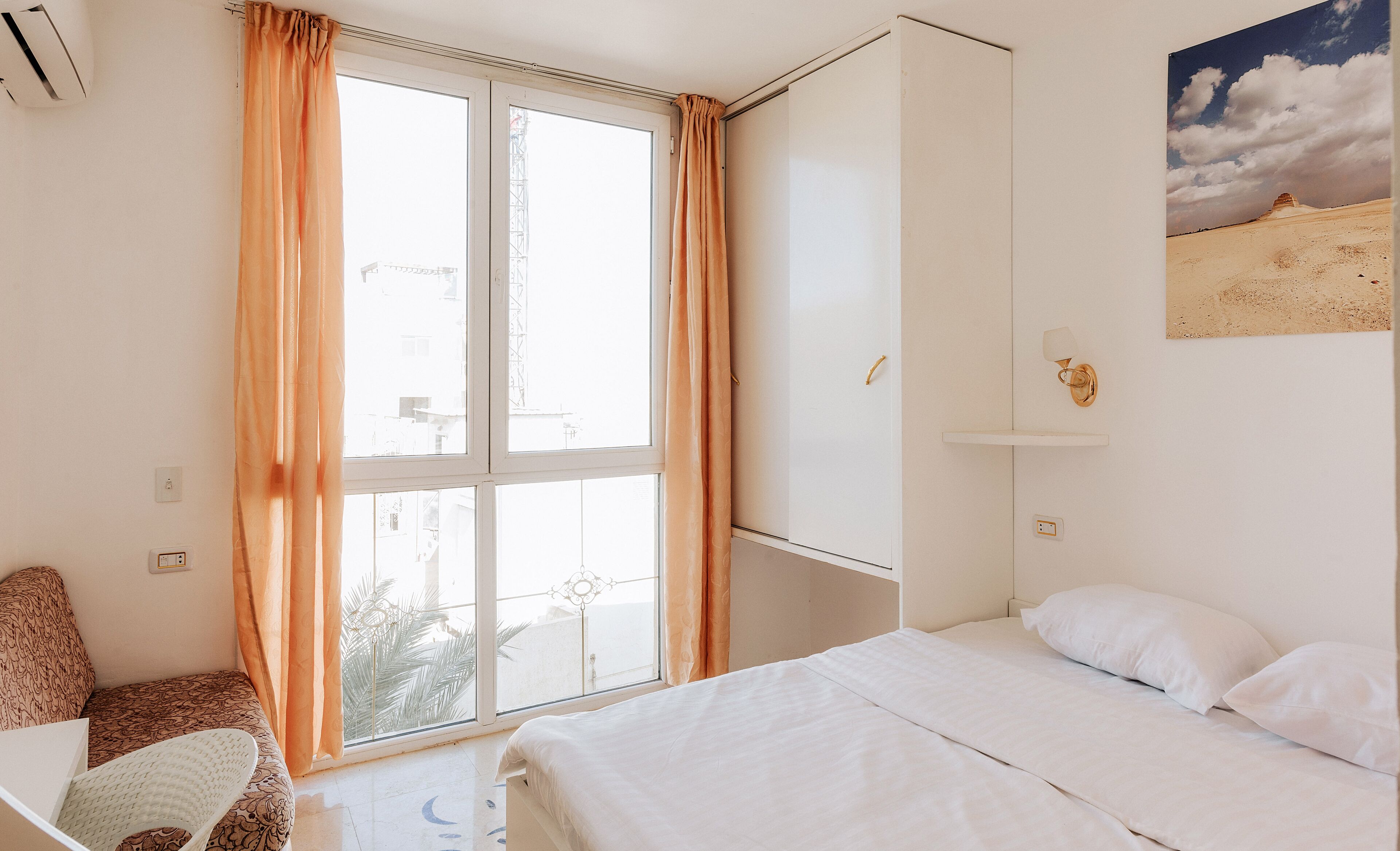 Un dormitorio con cama, escritorio y ventana con cortinas.