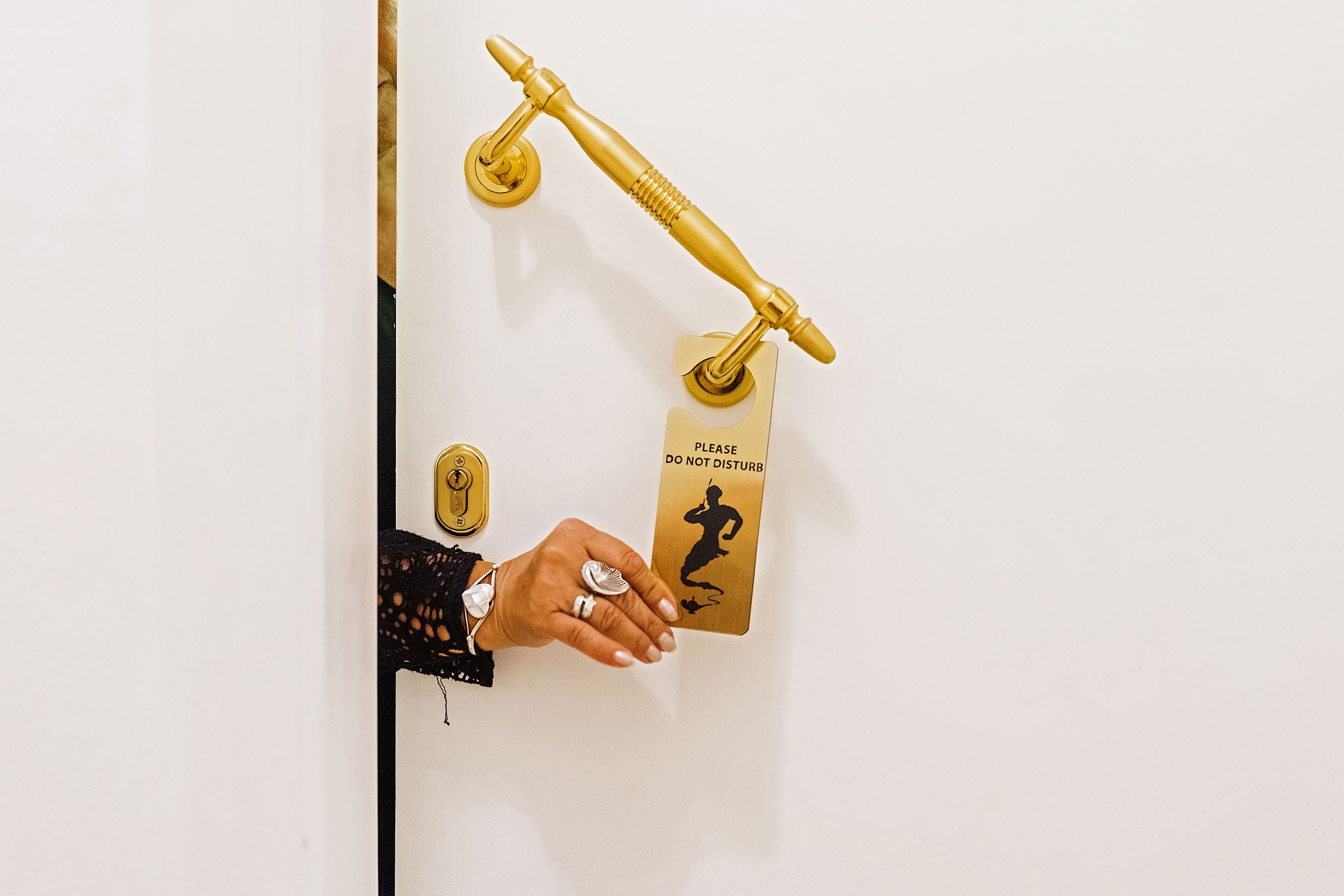 A hand holding a golden key, a golden door handle, and a sign that says "PLEASE DO NOT DISTURB".
