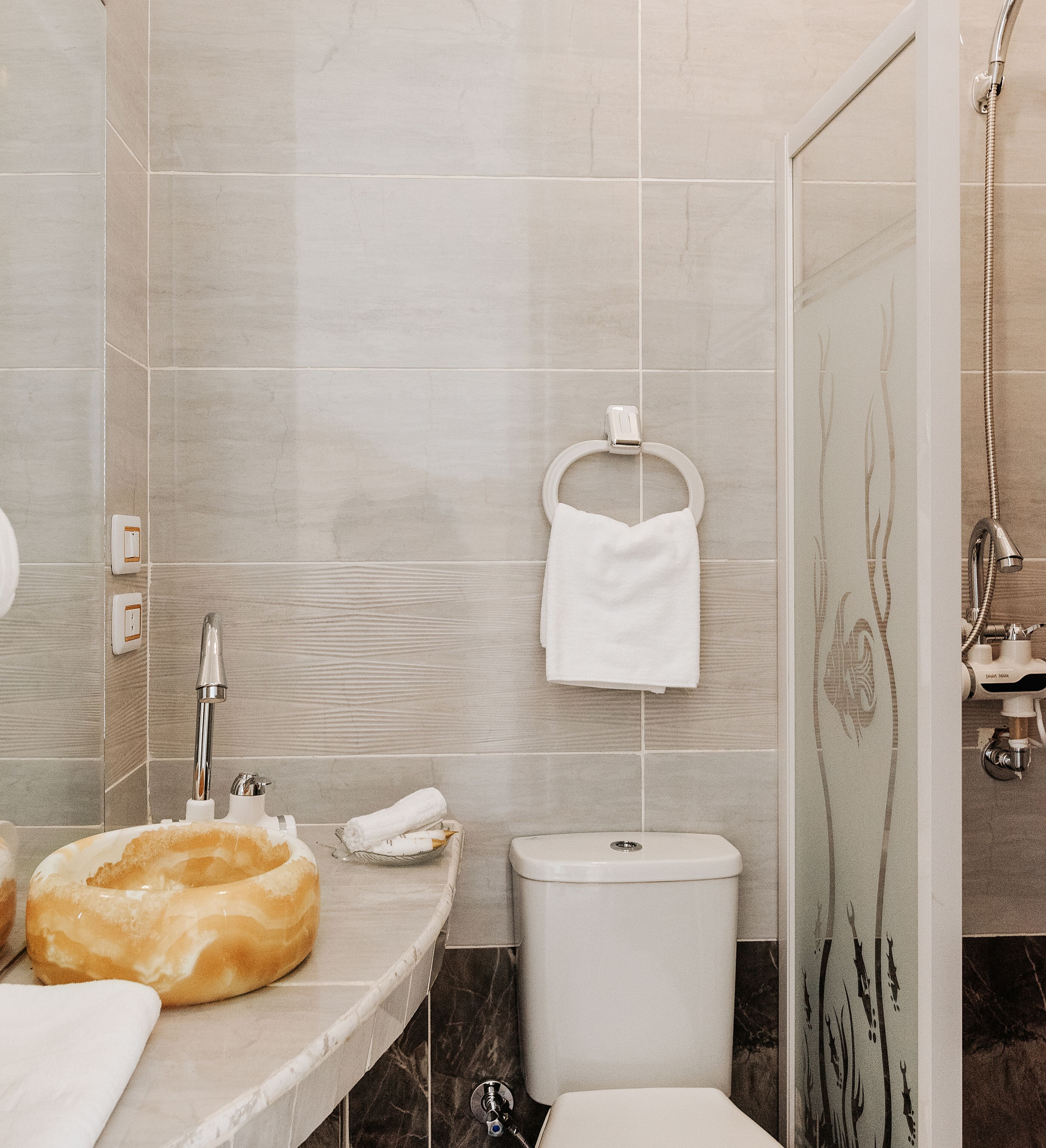 Ein Badezimmer mit Marmorwaschtisch, Toilette und Duschbereich.