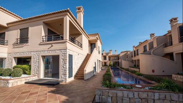 A modern residential building with a swimming pool, stone accents, and a clear blue sky. - Apt. Arribas, with pool and indoor heated pool (Praia da Luz)