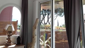 A room with a large window, a wooden ceiling, and a rustic branch decoration. - Apartment t2 type maisonette with garden sea view  (Theoule Sur Mer)
