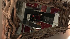 A mirror with a natural wood frame reflecting a kitchen area. - Apartment t2 type maisonette with garden sea view  (Theoule Sur Mer)