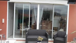 A patio area with wicker furniture and a table, a sliding glass door leading to an outdoor space, and a wooden cabinet. - Apartment t2 type maisonette with garden sea view  (Theoule Sur Mer)