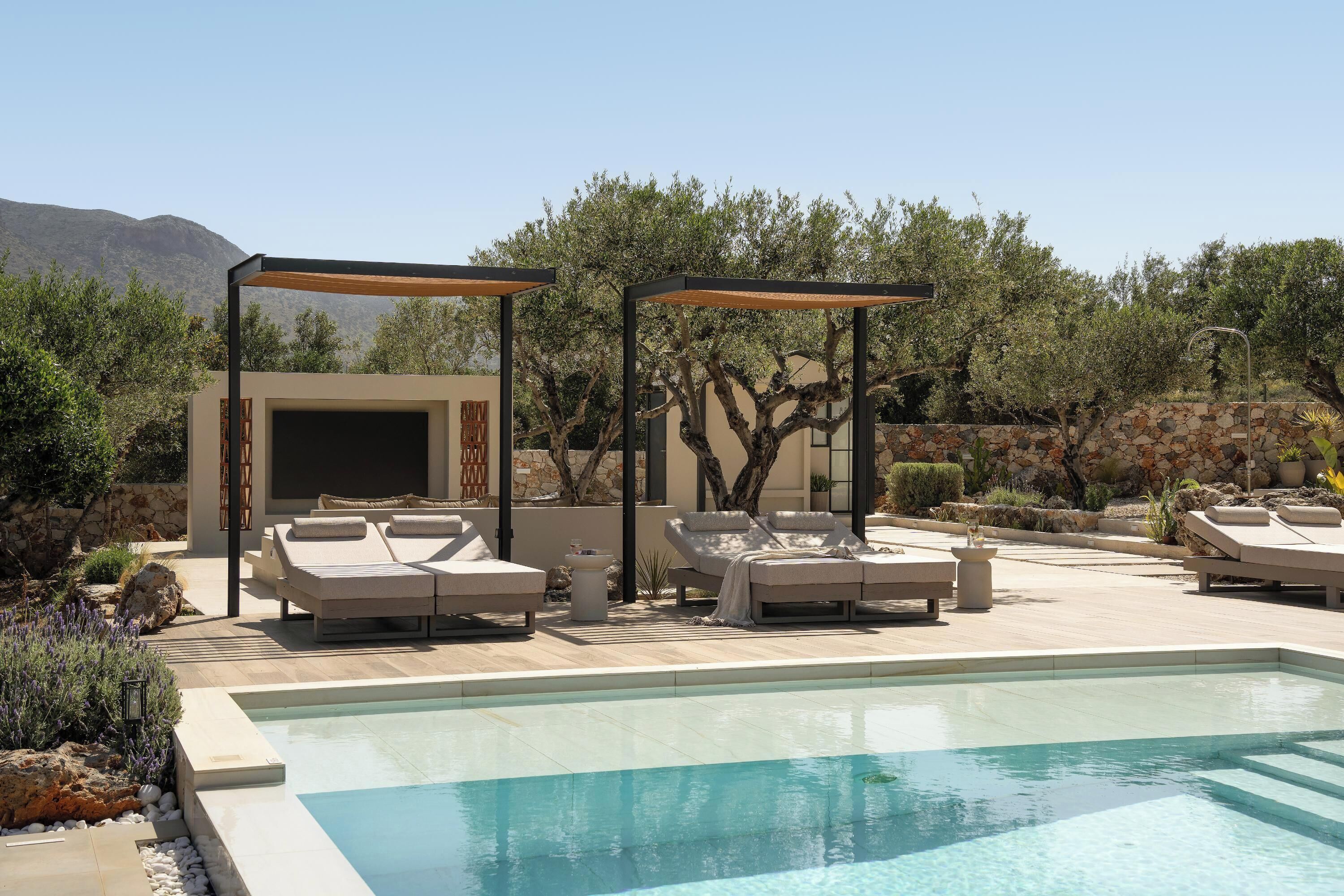 Ein Poolbereich mit Liegestühlen, einer Pergola und einer Steinmauer.