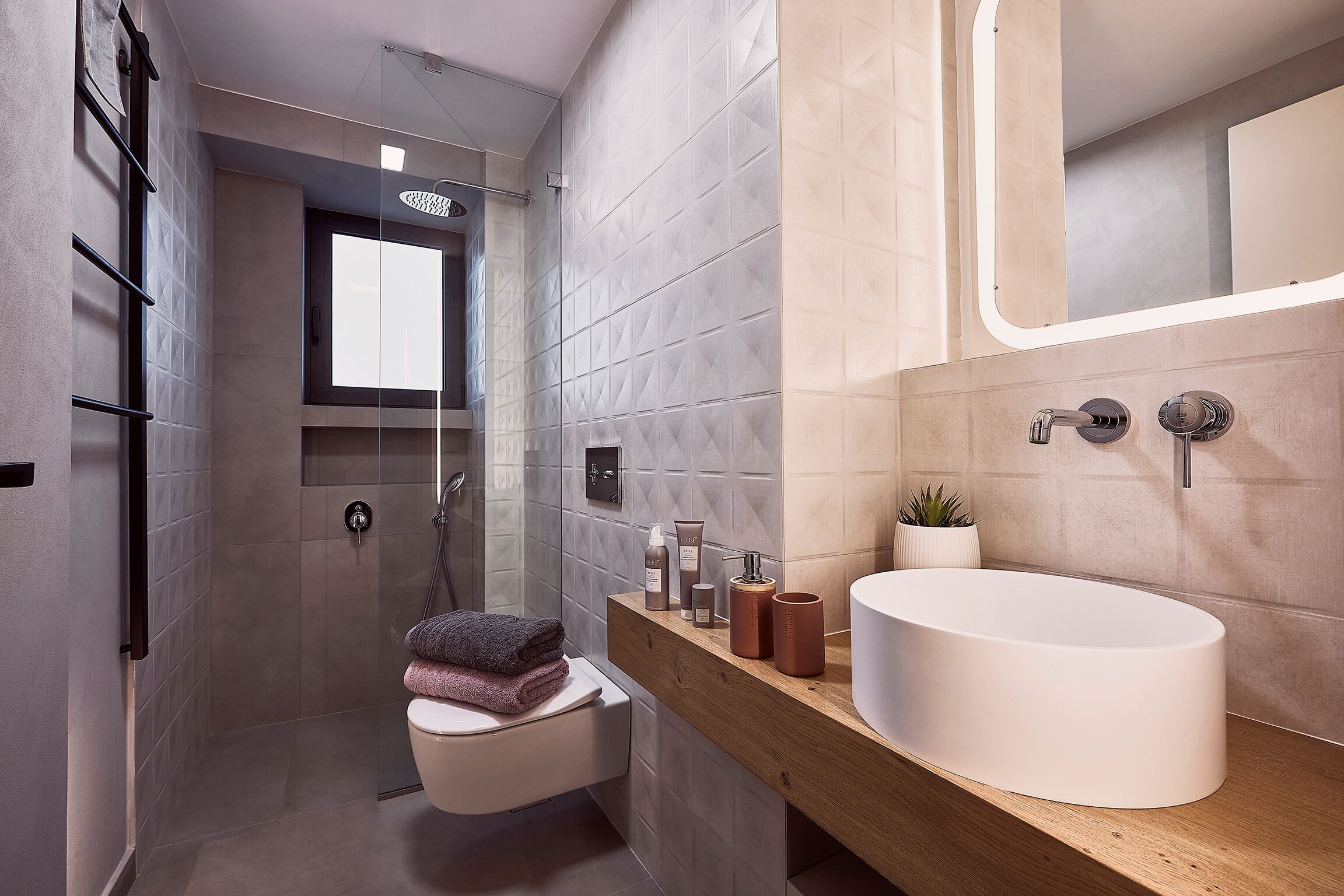 A modern bathroom with a large sink, a glass shower enclosure, and a wooden vanity.
