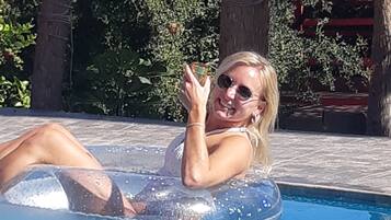 Una persona en una piscina con agua azul cristalina, rodeada de árboles y una estructura de madera.