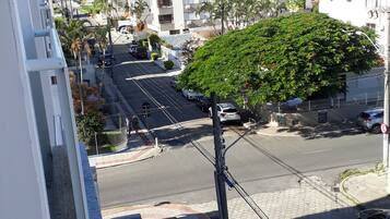 A street view with a tree-lined road, buildings, and a mountain in the background.