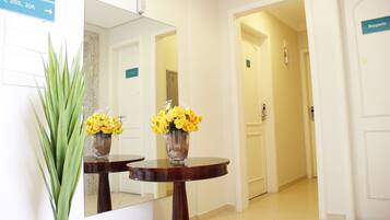 A hallway with a mirror reflecting a room, a sign with room numbers, and a door labeled "Rouparia".
