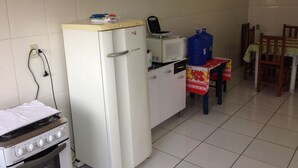 Una cocina compacta equipada con refrigerador, microondas, estufa y una mesa con sillas.