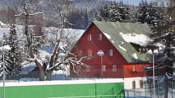 Ein rotes Backsteingebäude mit einem grünen Zaun in einer verschneiten Landschaft.