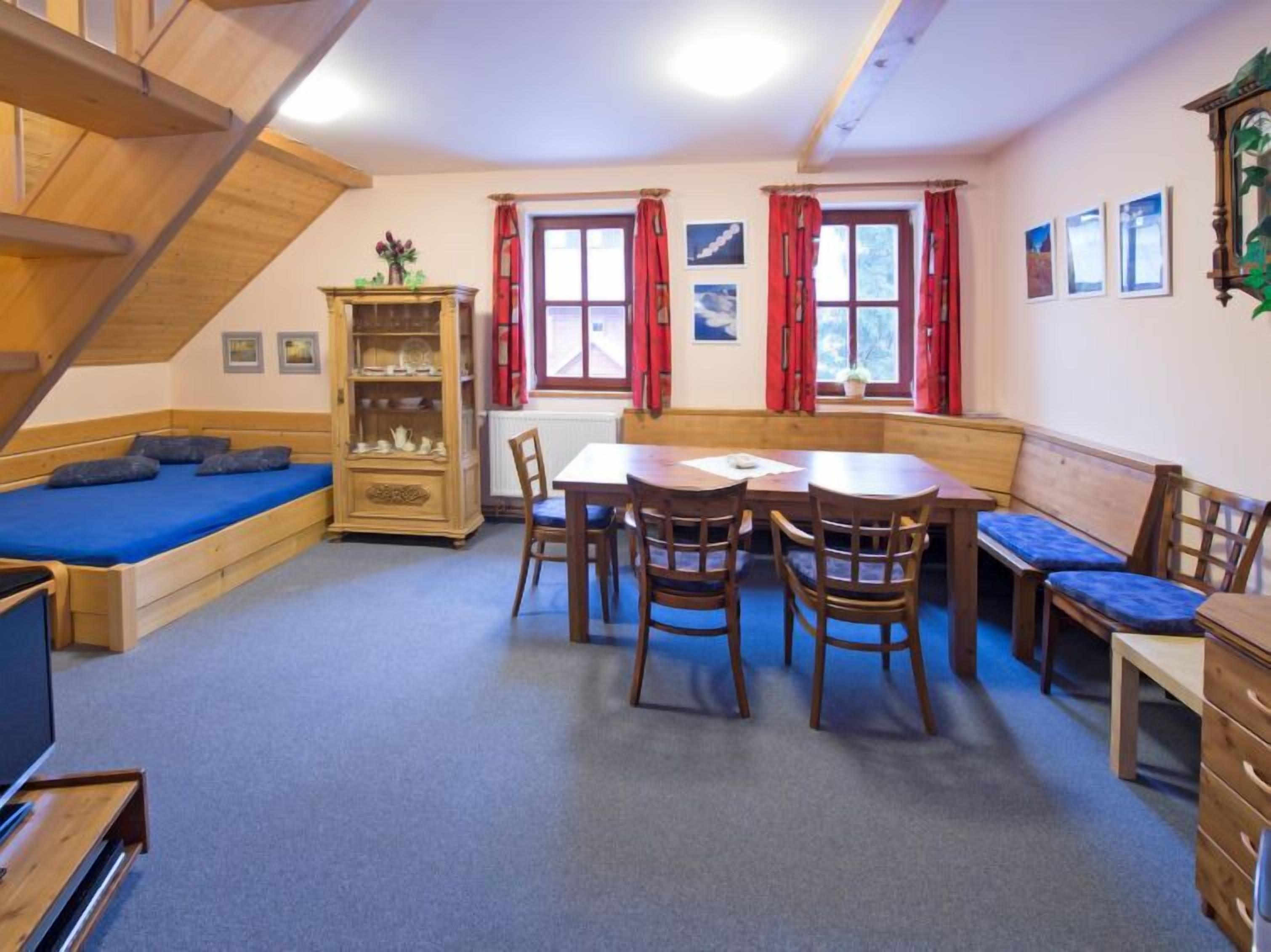 A cozy room with a wooden bed, a dining table with chairs, a built-in bench, and a wooden cabinet.