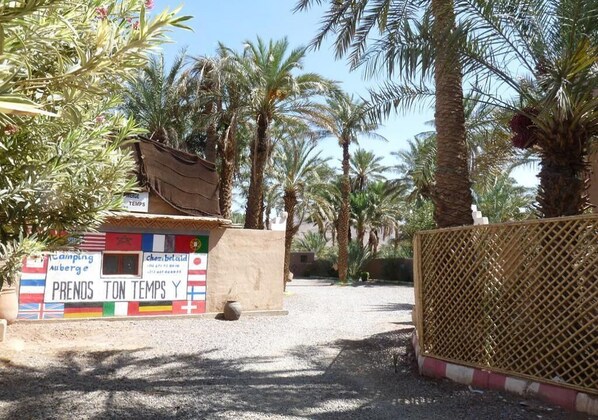 A campsite with a signboard displaying various flags and the text "PRENOS TON TEMPS Y".