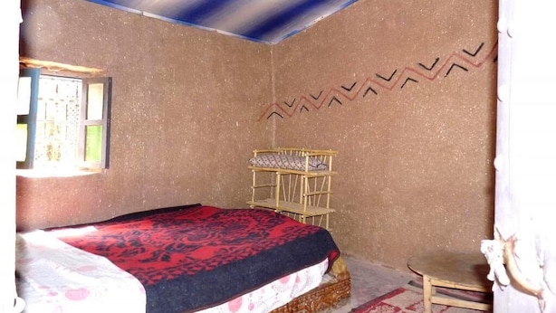 A bedroom with a bed, a small wooden chair, a window, and a wall decoration. - Hostel Take Your Time 4220 (Zagora)