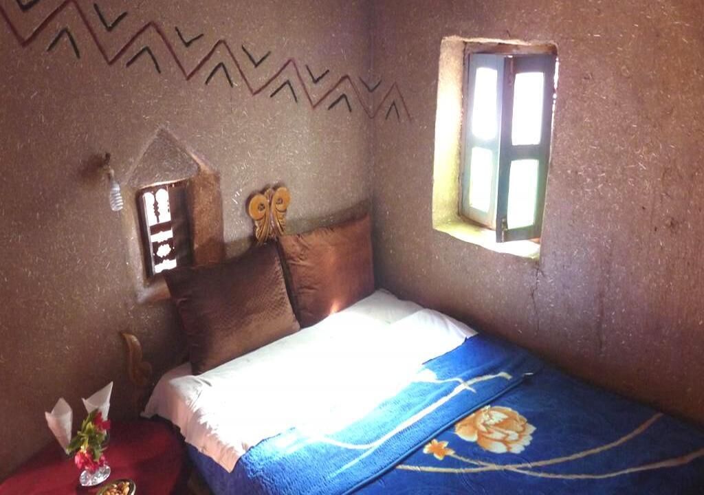 Une petite pièce agréable, avec un lit, une fenêtre et un élément décoratif au mur.