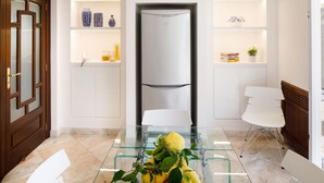 Une cuisine moderne dotée d’un réfrigérateur encastré, de meubles blancs et d’une table à manger en verre agrémentée d’un élément décoratif central.