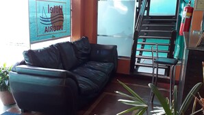 Et hotel lobby med en sort lædersofa, en trappe og en brandslukker.